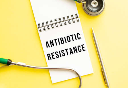 ANTIBIOTIC RESISTANCE is written in a notebook on a color table next to pen and a stethoscope. medical conceptの写真素材