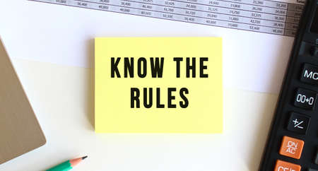 Notepad with the text KNOW THE RULES on the desktop, near the laptop, calculator.の写真素材