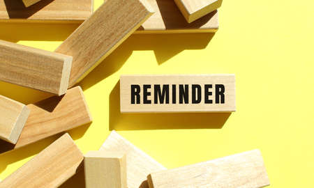 REMINDER text written on a wooden blocks on a yellow background.の写真素材