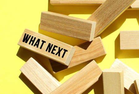 The WHAT NEXT text is written on one of the many scattered wooden blocks, against a yellow background.の写真素材
