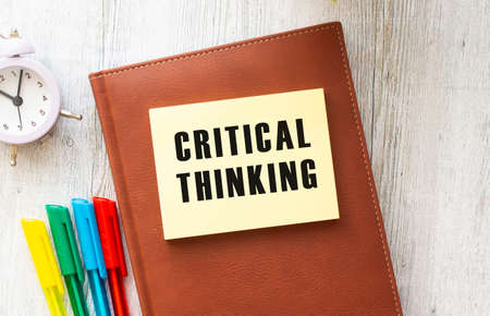Notepad with text CRITICAL THINKING on a white background, near laptop, calculator and office supplies. business concept.の写真素材
