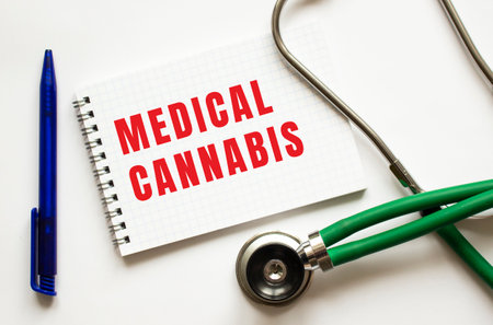 MEDICAL CANNABIS is written in a notebook on a white table next to pen and a stethoscope. medical conceptの写真素材