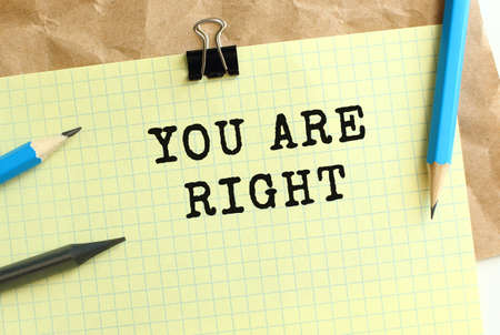 YOU ARE RIGHT lettering on a yellow sheet of paper over crumpled kraft paper. Pencils and paper clip. business concept.の写真素材