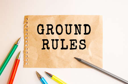 A sheet of kraft paper torn from a notebook lies on the table. Text on GROUND RULES sheet. Colored pens and a pencil lie nearby. Concept for your design.の写真素材