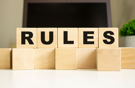 The word RULES is written on wooden cubes lying on the office table in front of a laptop. business concept.の写真素材