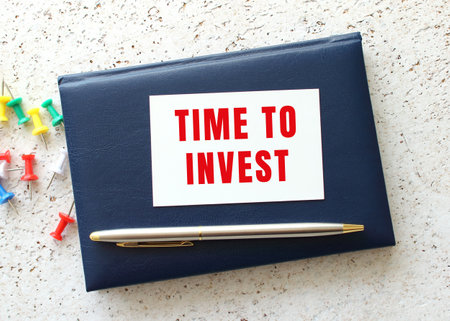 Text TIME FOR INVEST on a business card lying on a blue notebook next to the pen. business concept.の写真素材