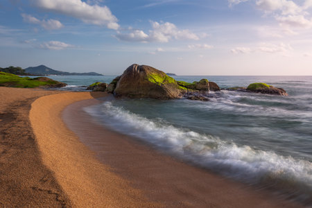 Picturesque sandy beach with granite rocks overgrown with vivid seaweed at sunrise, Samui, Thailandの写真素材