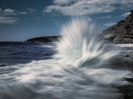 Long exposure shot of waves crashing against coastal rocks look like a water blastの写真素材