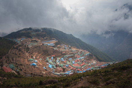 Small town on mountainside in Himalayas like amphitheater under low clouds, Namche Bazaar, Nepal