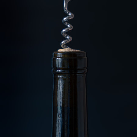 Long narrow neck of wine bottle with corkscrew inserted into cork isolated on black backgroundの写真素材