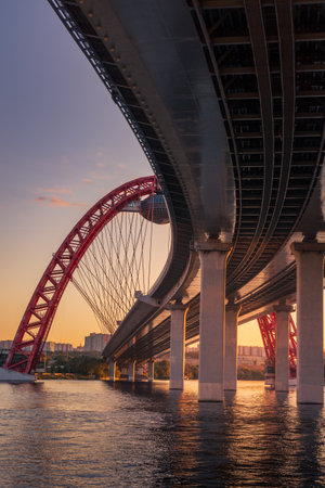 Sunset cityscape with modern arched cable stayed bridge reflecting in river water, Moscow, Russiaの写真素材