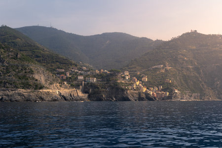 Ligurian coastline with forested mountain steep cliffs colorful village by water, Cinque Terre, Italyの写真素材