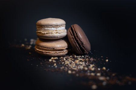 Still life with three macaron cookies on nut crumbs isolated against dark backgroundの写真素材