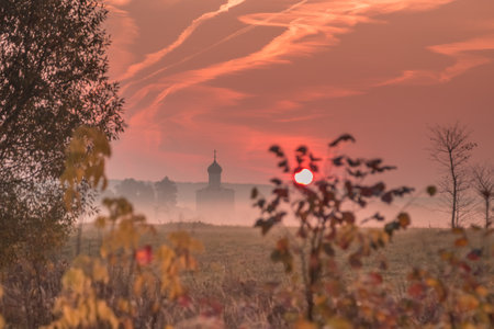 The colorful foggy rural landscape at sunrise with a silhouette of an ancient Russian churchの写真素材