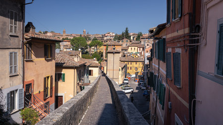 Narrow pedestrian street between old brick houses in ancient Italian city on sunny day, Perugia, Italyの写真素材