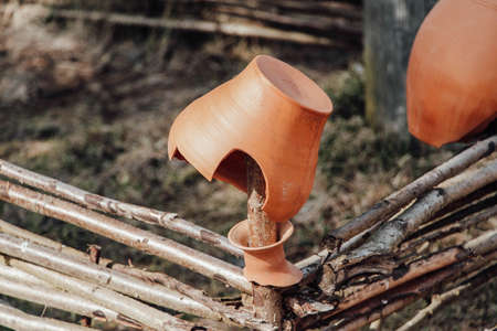 The remains of an old clay pot hang on a wicker fenceの写真素材