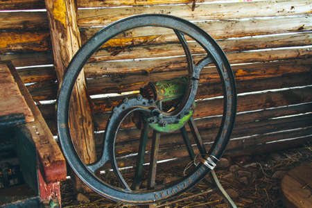 Steel old rusty wheel from agricultural machinery near wooden wall