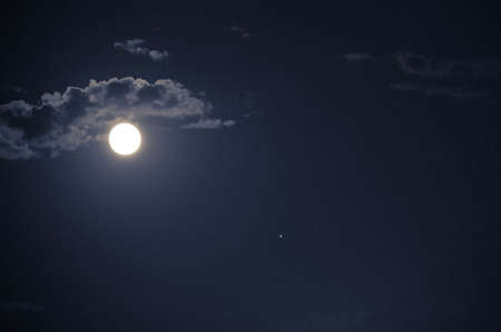 Full moon in the night blue sky with clouds