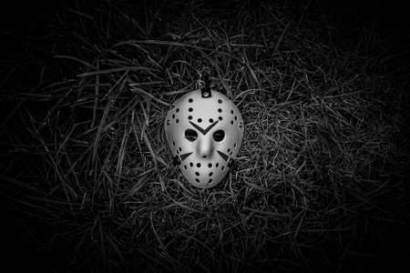 Creepy white hockey mask lays on the ground in BW