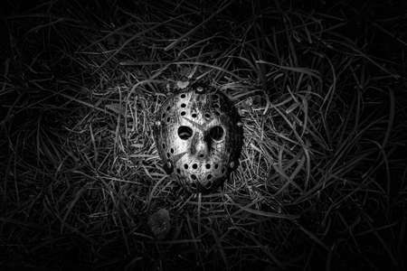 Creepy steel hockey mask lays on the ground in BWの写真素材