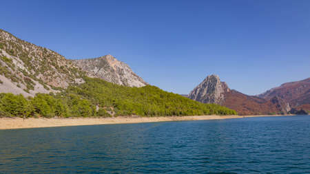 View of the green water of the Oymapinar Dam with green trees on the shore