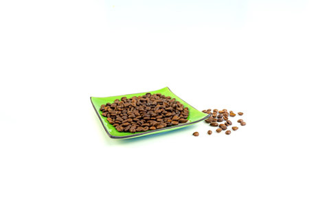Coffee beans on a green square saucer, white backgroundの写真素材