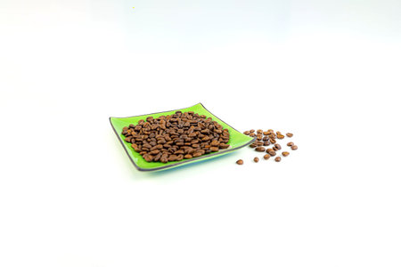 Coffee beans on a green square saucer, white backgroundの写真素材