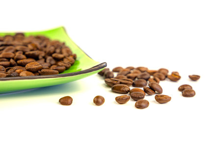 Coffee beans on a green square saucer, white backgroundの写真素材