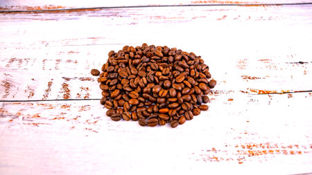 coffee beans folded into a heart on a white wooden backgroundの写真素材