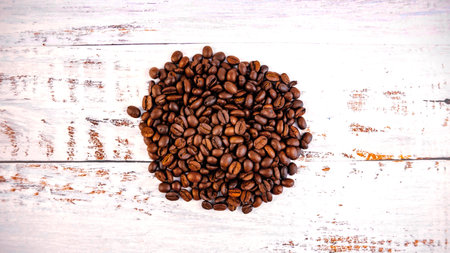 coffee beans folded into a heart on a white wooden backgroundの写真素材