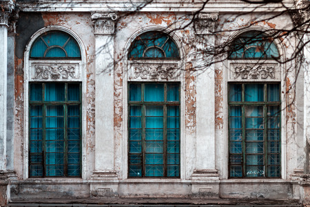Facade of old abandoned building with large arched windows and columnsの写真素材