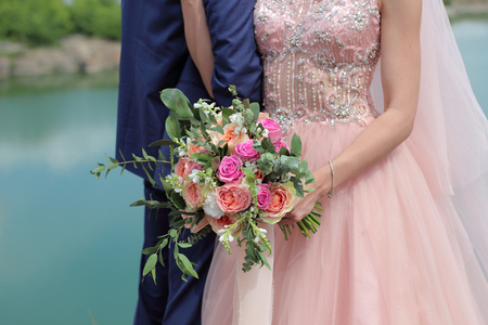 Beautiful bridal bouquet in hands of the bride. Wedding bouquet of peach roses by David Austin,  single-head pink rose aqua, eucalyptus, ruscus, gypsophilaの写真素材