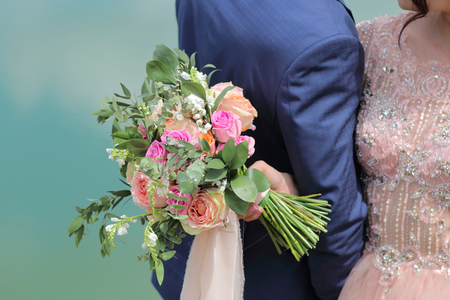 Beautiful bridal bouquet in hands of the bride. Wedding bouquet of peach roses by David Austin,  single-head pink rose aqua, eucalyptus, ruscus, gypsophilaの写真素材