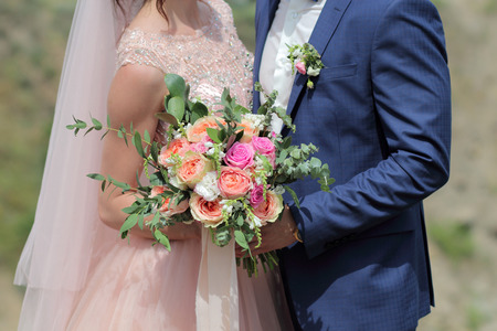 Bride holding a beautiful bridal bouquet. Wedding bouquet of peach roses by David Austin,  single-head pink rose aqua, eucalyptus, ruscus, gypsophilaの写真素材