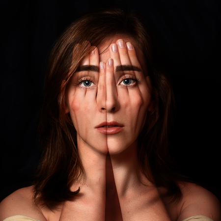 Surreal portrait of a young girl covering  her face and eyes with  her hands.Double exposureの写真素材