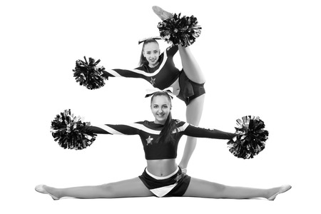 Two professional cheerleaders posing at studio. Side split and vertical split. Isolated over white.Black and white photographyの写真素材