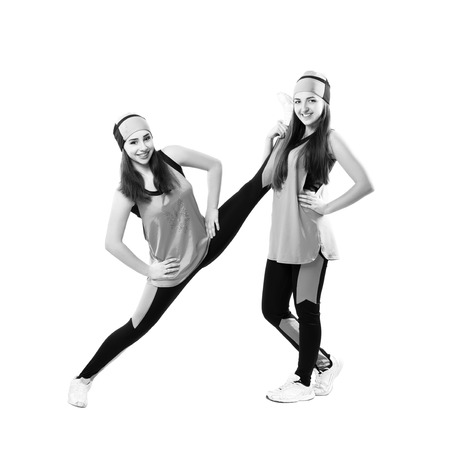 Two young professional cheerleader are stretched before performance. Isolated over white. Black and white photographyの写真素材
