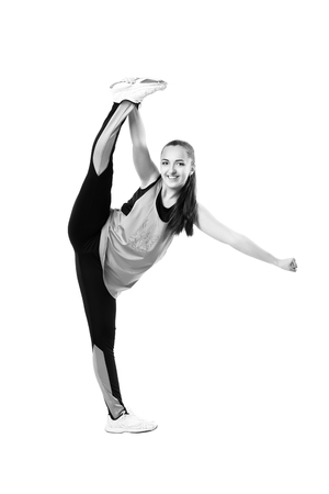 Young professional cheerleader  stands in vertical splits. Isolated over white. Black and white photographyの写真素材