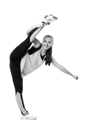 Young professional cheerleader  stands in vertical splits. Isolated over white. Black and white photographyの写真素材