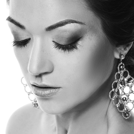 Close-up portrait of young closing eyes woman's face with clean fresh skin,woman with jewelry, isolated on white background.の写真素材