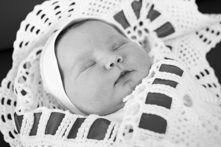 Newborn baby sleeping on a changing table.Black and white photographyの写真素材