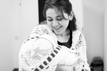 Young mother looking at newborn daughter in the hall of the perinatal center.Black and white photographyの写真素材