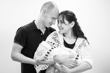 Happy couple holding their newborn daughter in her arms in the hall of the perinatal center.Black and white photographyの写真素材