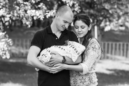 Happy couple holding their newborn daughter in her arms. Outdoors.Black and white photographyの写真素材