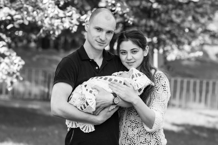 Happy couple holding their newborn daughter in her arms. Outdoors.Black and white photographyの写真素材