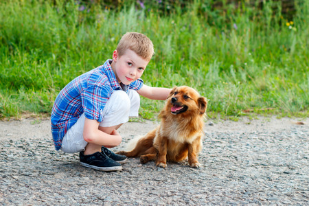 boy in a plaid shirt hugging a red fluffy dog. Best friends. Outdoorの写真素材