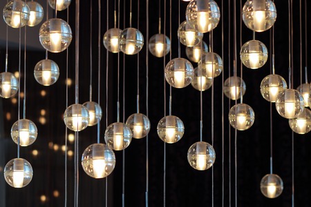 lighting balls on the chandelier in the lamplight,  light bulbs hanging from the ceiling, lamps on the dark background, selective focus, horizontalの写真素材