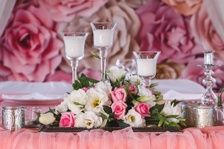 wedding table decorated with fresh flowers, candles and silver cups. Paper flowers in the backgroundの写真素材