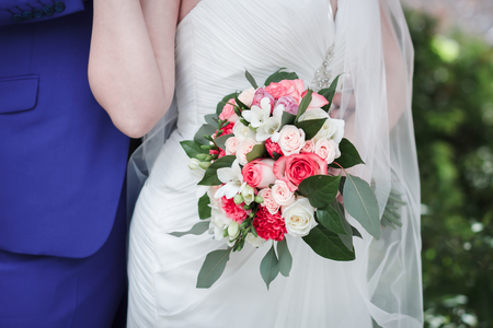 Wedding bouquet of roses, freesias and carnations in the hands of the brideの写真素材