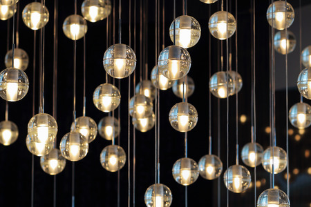 lighting balls on the chandelier in the lamplight,  light bulbs hanging from the ceiling, lamps on the dark background, selective focus, horizontalの写真素材